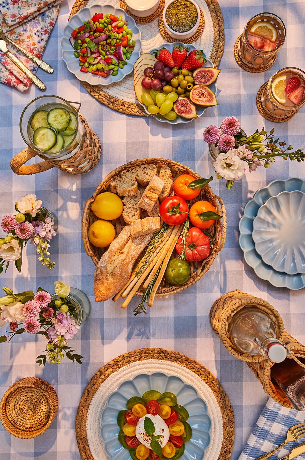 Table with blue gingham tablecloth, plates and baskets of food