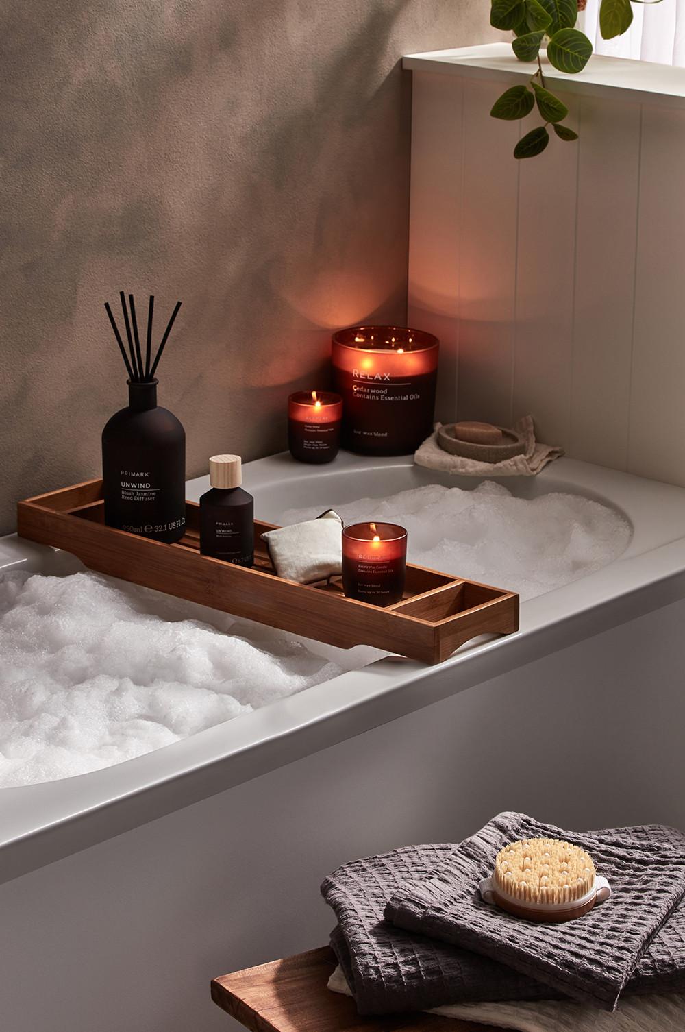 Bathroom set up, with candles, wooden bath shelf and body brush