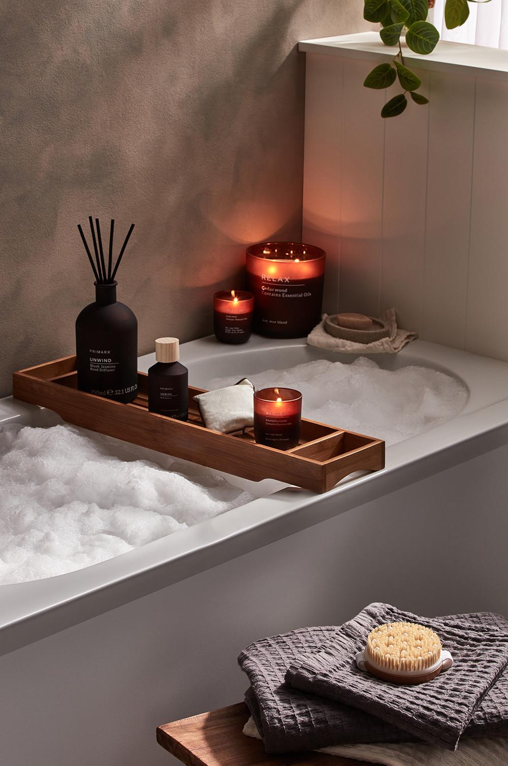 Badezimmer mit Kerzen, Badewannenablage aus Holz und Körperbürste