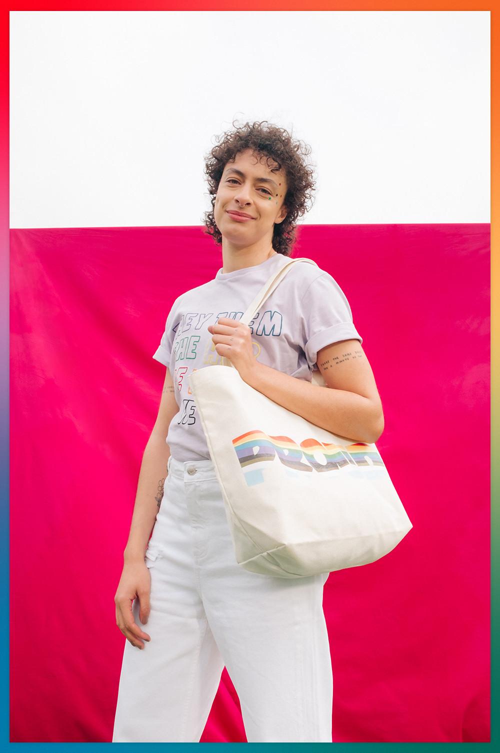 T-shirt viola con pronomi e borsa tote con scritta "Proud"