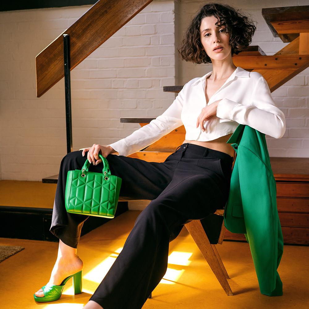 Model wears white shirt, black trousers paired with green accessories