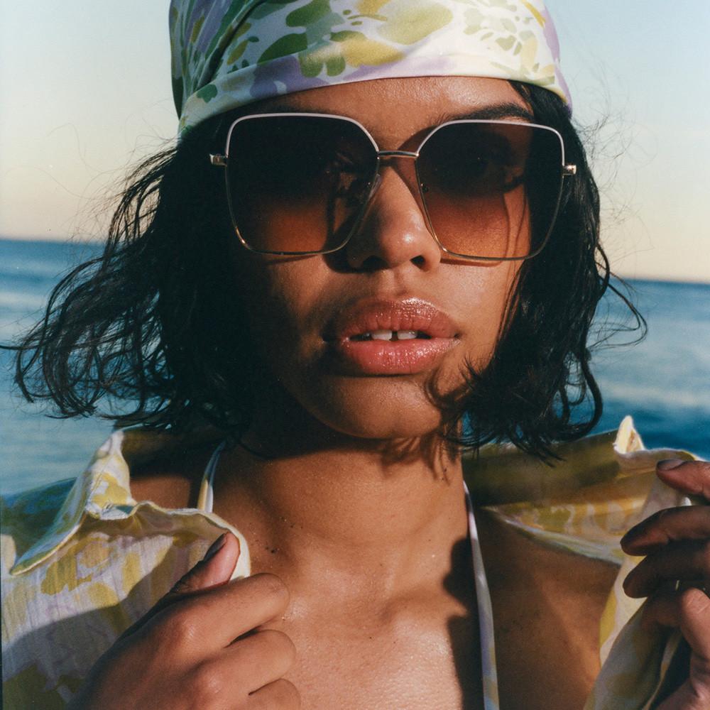Model wears sunglasses and headscarf on the beach