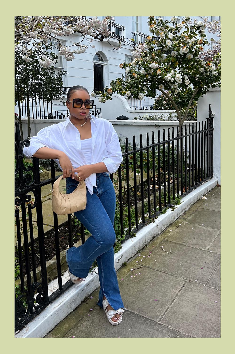 @sharayethomas wearing blue flared jeans, sandals, white shirt, crop top and beige bag