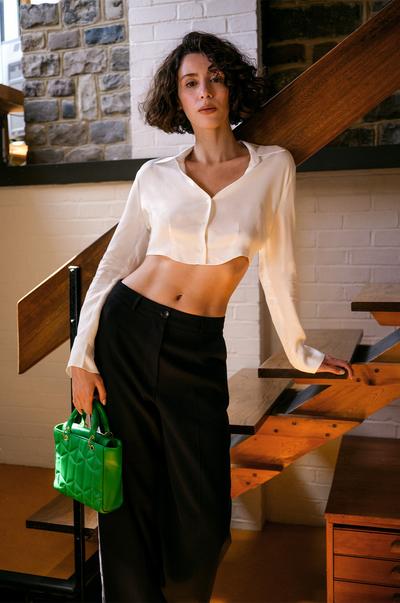 Model wears white shirt, black pants, green accessories
