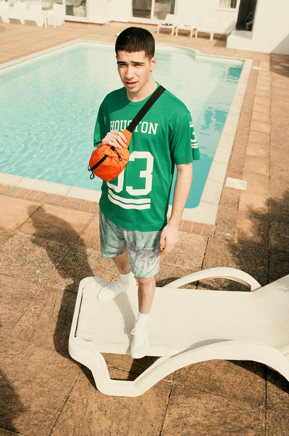 Man in graphic tee, swim shorts and accessories