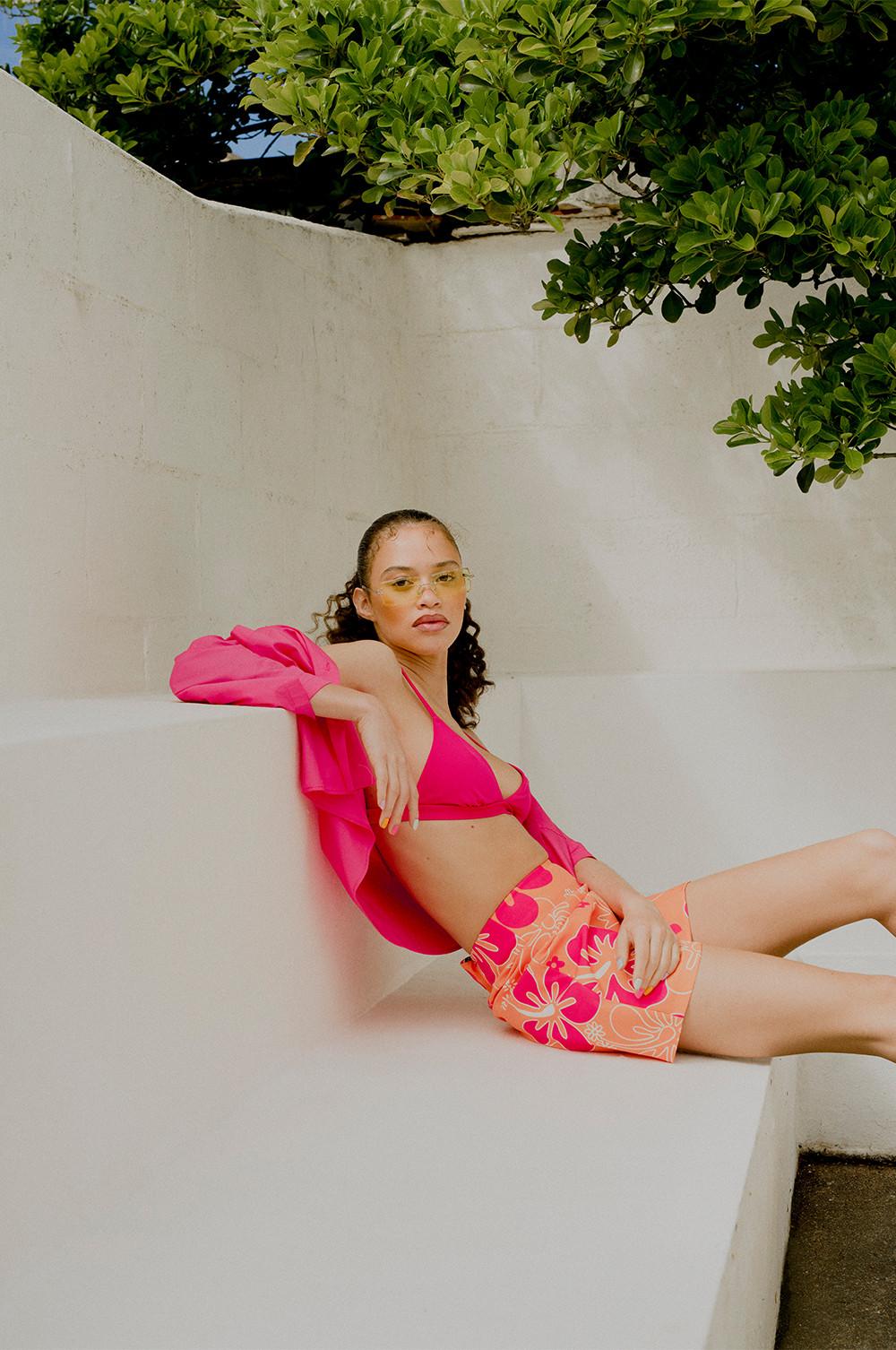 Model wears printed shorts paired with pink bralette and shirt