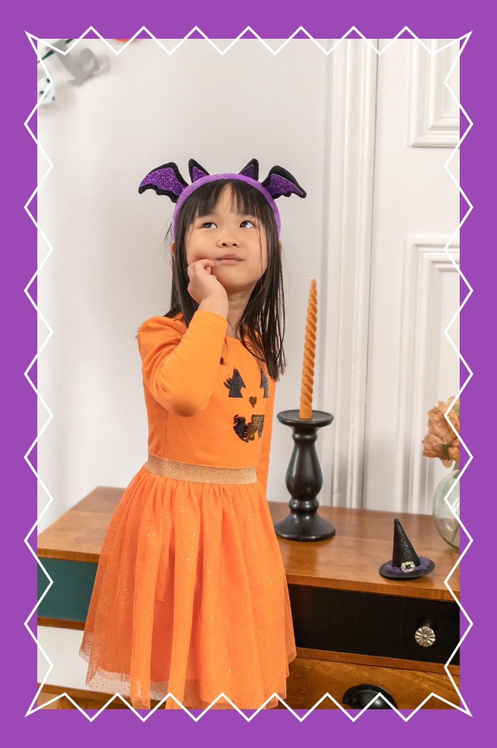 Child wears pumpkin dress with bat headband