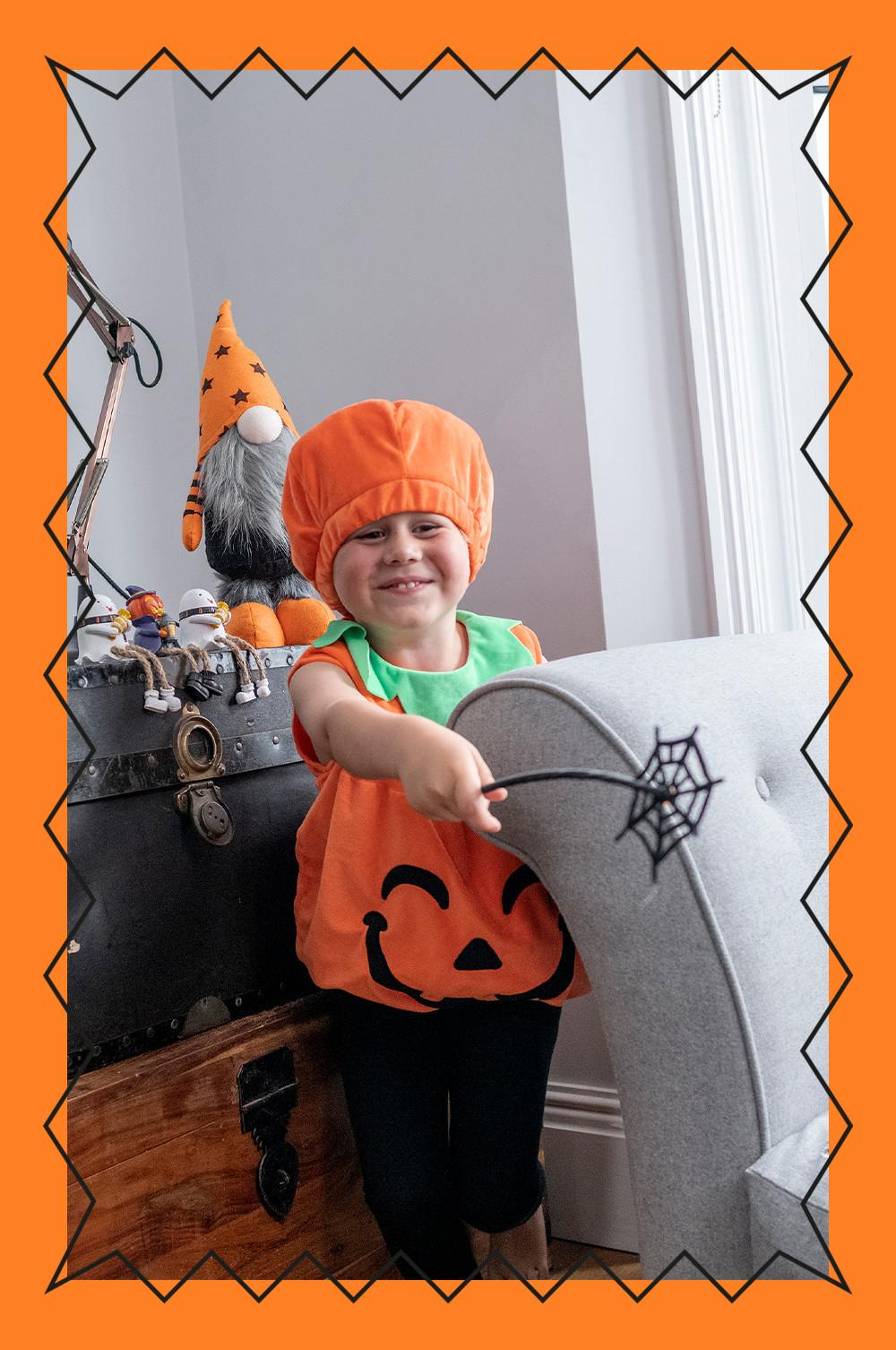 Child wears plush pumpkin bodysuit with hat
