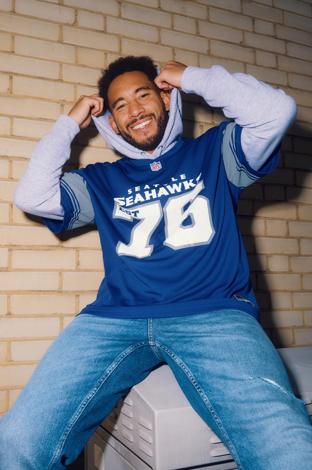 Josh Densel in blauem Seahawks-Oberteil über grauem Kapuzenpullover