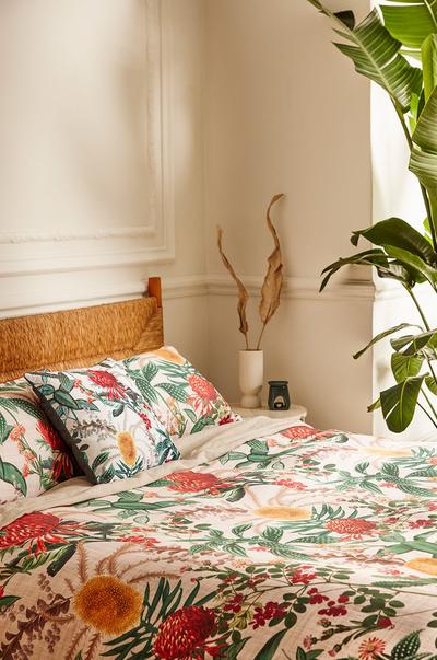Cenário de cama com lençóis com estampado floral e vasos rústicos