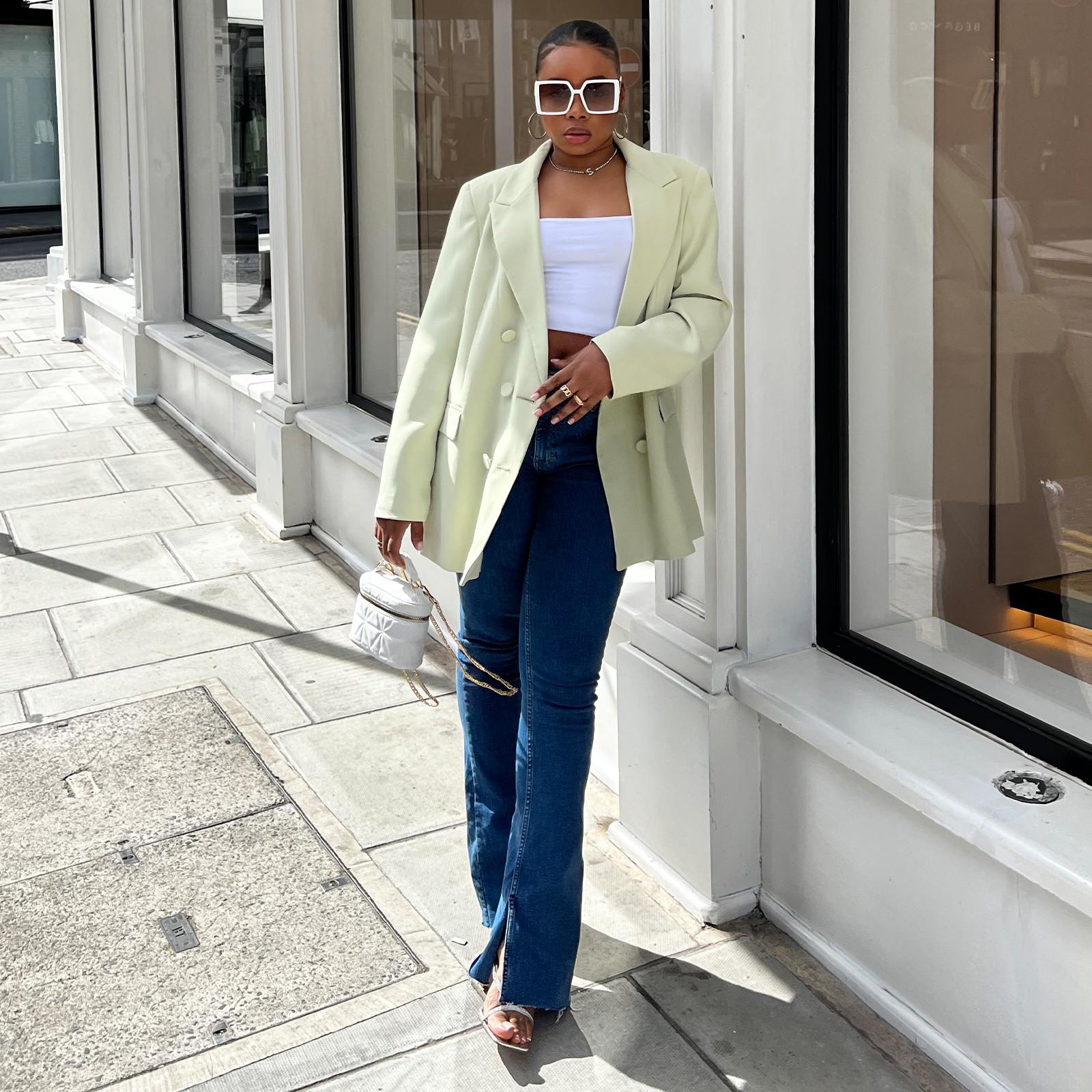 Woman wearing flared jeans, green blazer and top