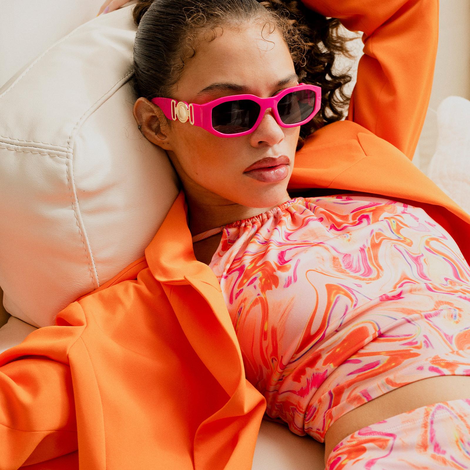 La modella indossa un abito rosa e arancione con stampa a vortici e una camicia arancione.