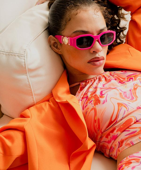 Model wears pink and orange printed two piece with coordinating orange shirt