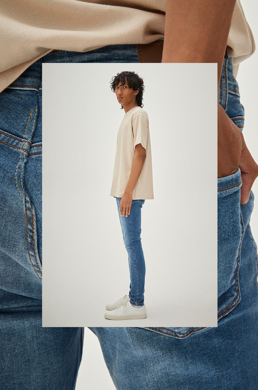 Model draagt blauwe skinny jeans met ecru oversized T-shirt