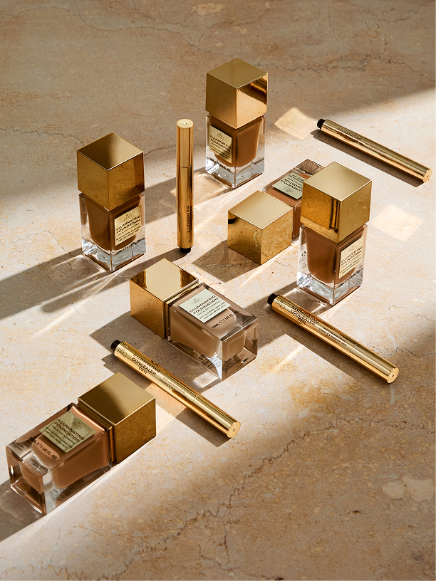 Three PS Cooling body mist bottles in orange, pink and green with water droplets on glass shelf.