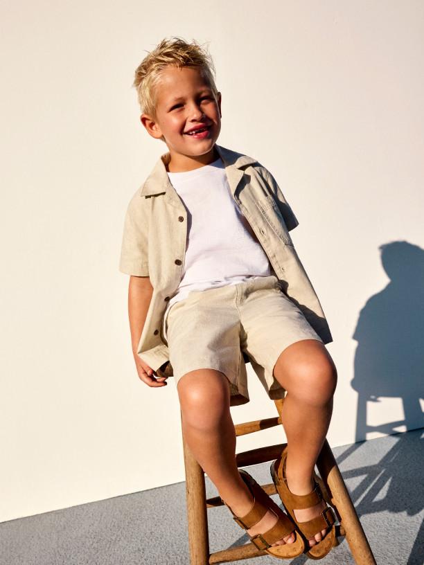 Child in pink tracksuit demonstrating martial arts stance with pink trainers against white background.