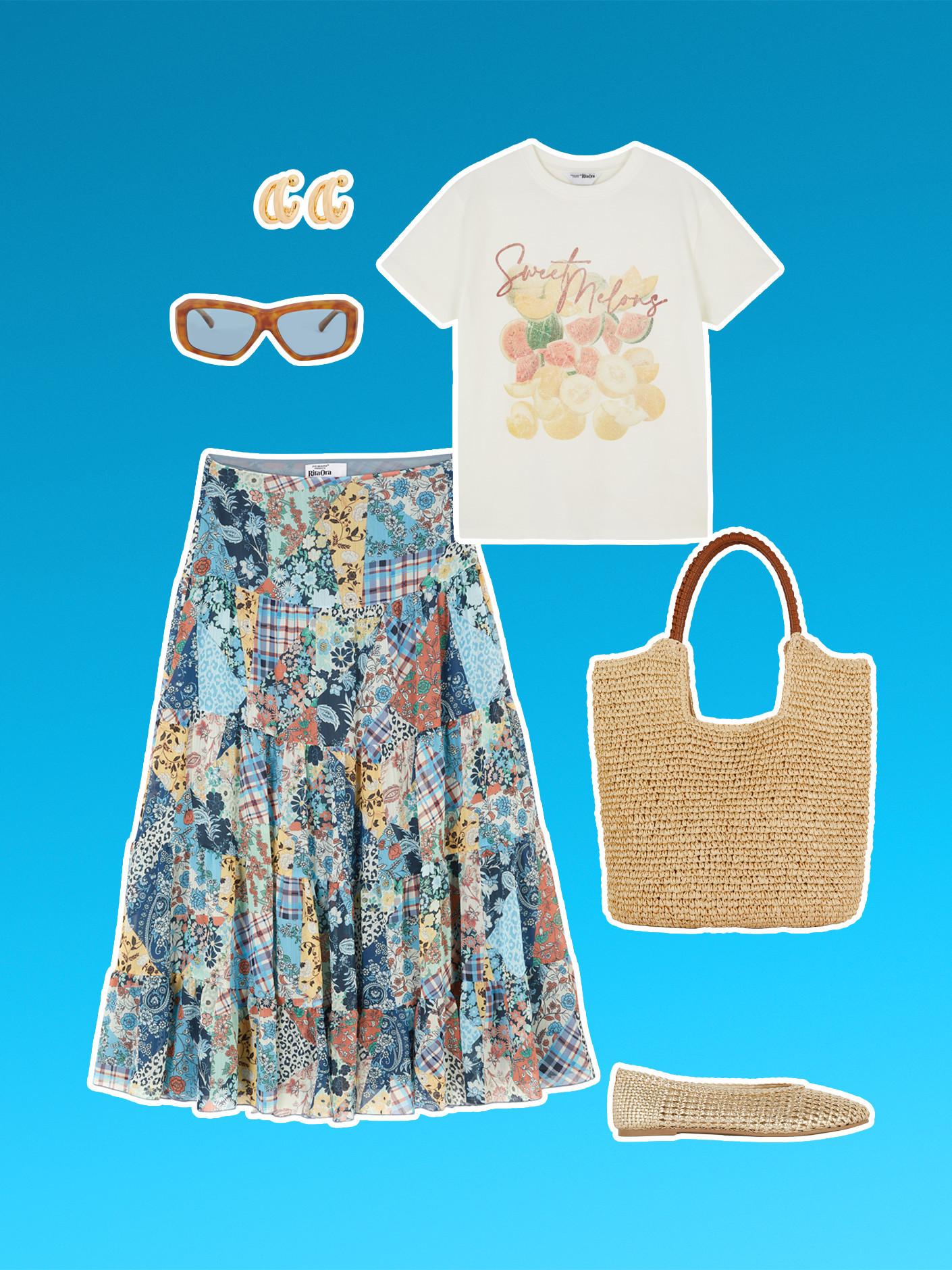 Completo estivo con gonna patchwork floreale, maglietta bianca con grafica, borsa tote di paglia, ballerine intrecciate, orecchini e occhiali da sole color oro.