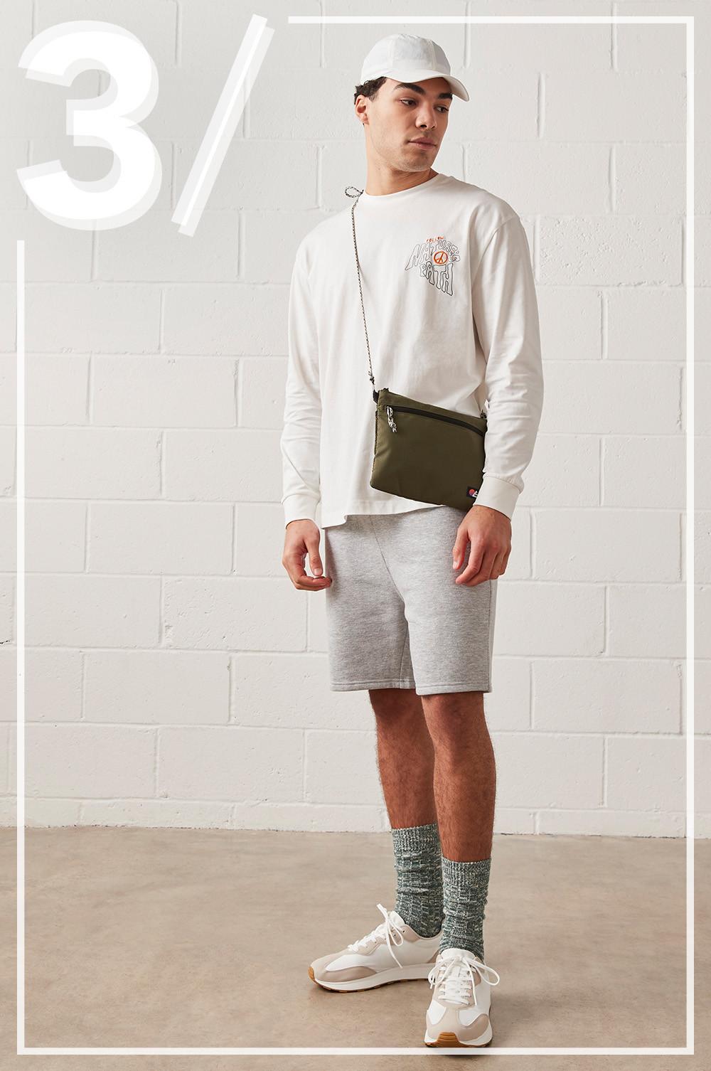 Model wears grey jogger shorts, long sleeved white top, with matching white cap