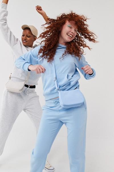Models wearing white and blue tracksuits, with coordinating crossbody bags
