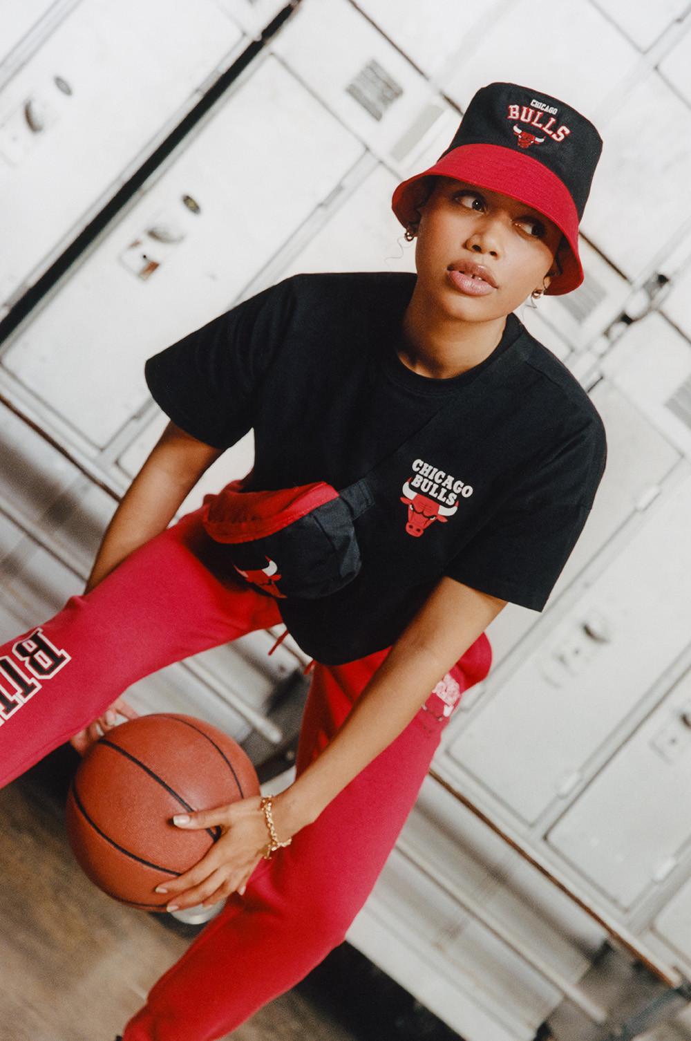 Model wears red NBA Bulls joggers, black NBA Bulls top, with red and black Bulls bucket hat