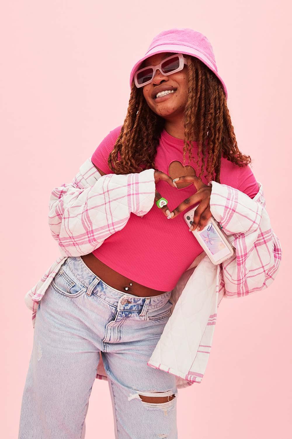 Model wears pink top, quilted pink shacket and bucket hat