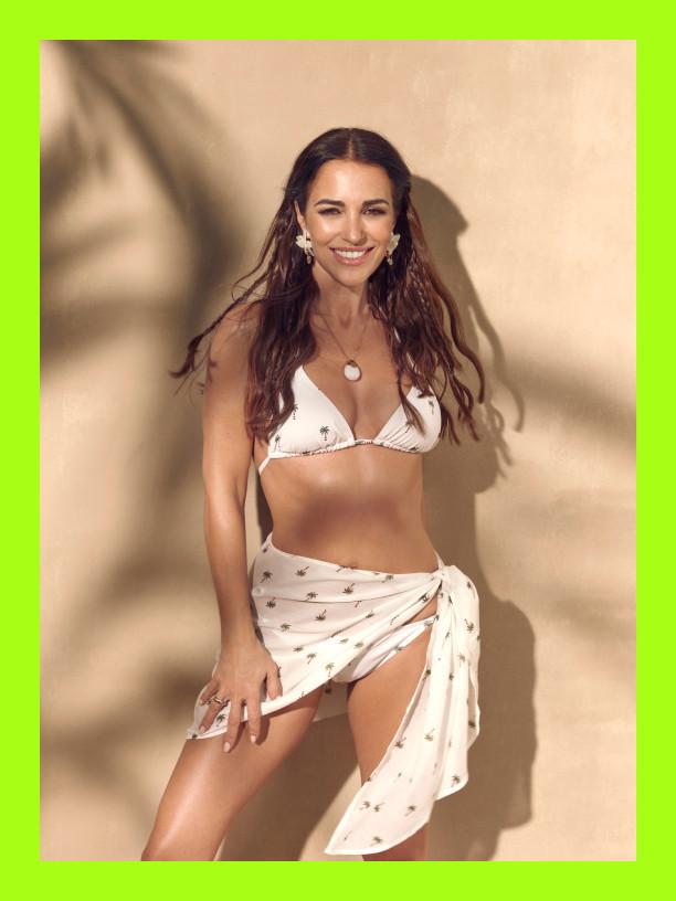 Woman smiling wearing a white star-print bikini with matching sarong wrap.