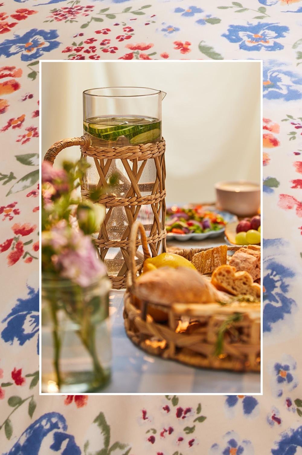 Présentation de table avec nappe à motif vichy bleu, carafes et paniers en rotin
