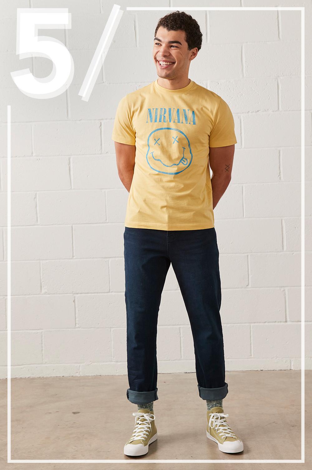 Model wears yellow Nirvana graphic tshirt, with dark blue straight leg jeans