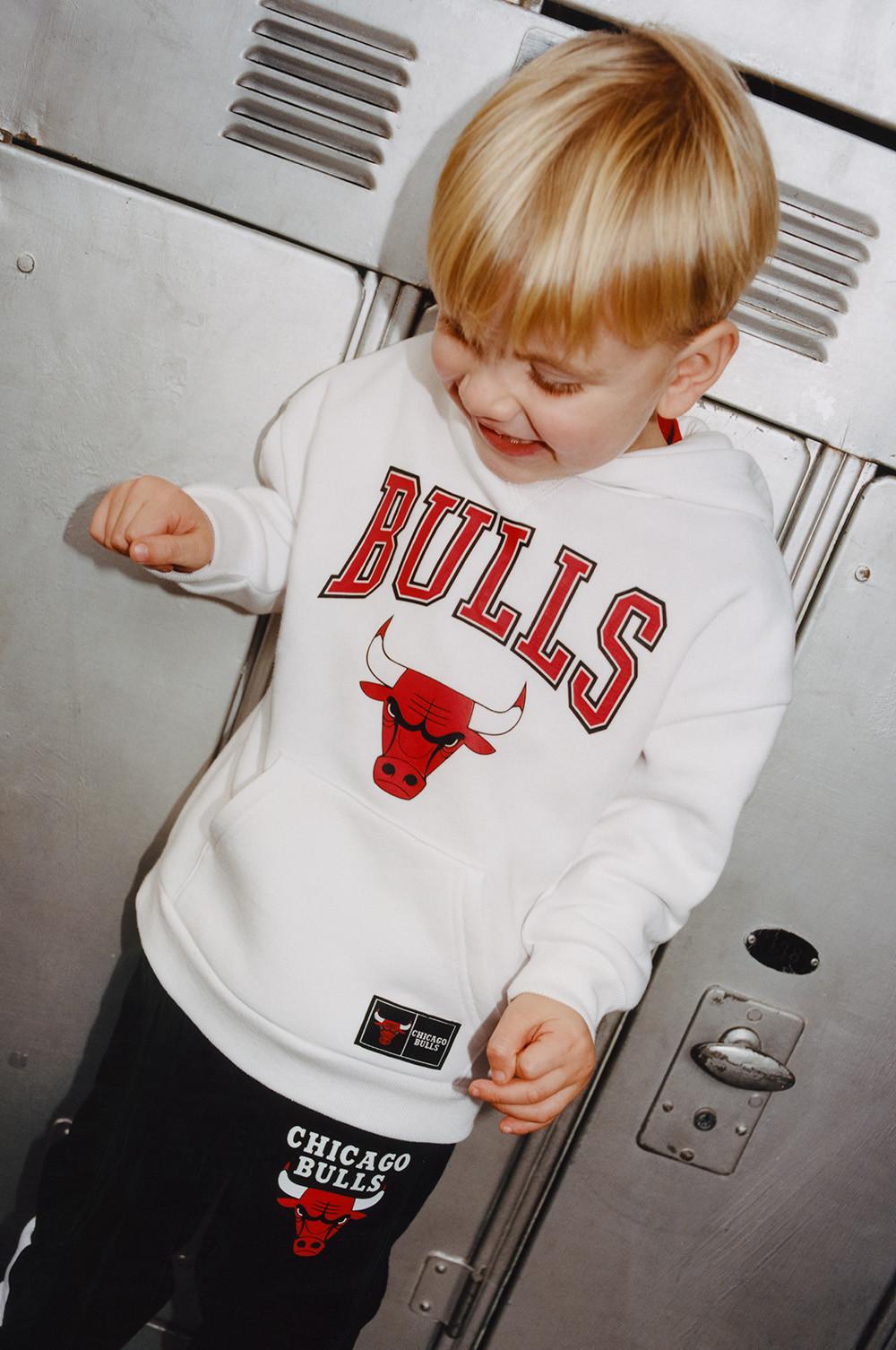 Child wears white NBA Bulls hoodie, with black NBA Bulls joggers