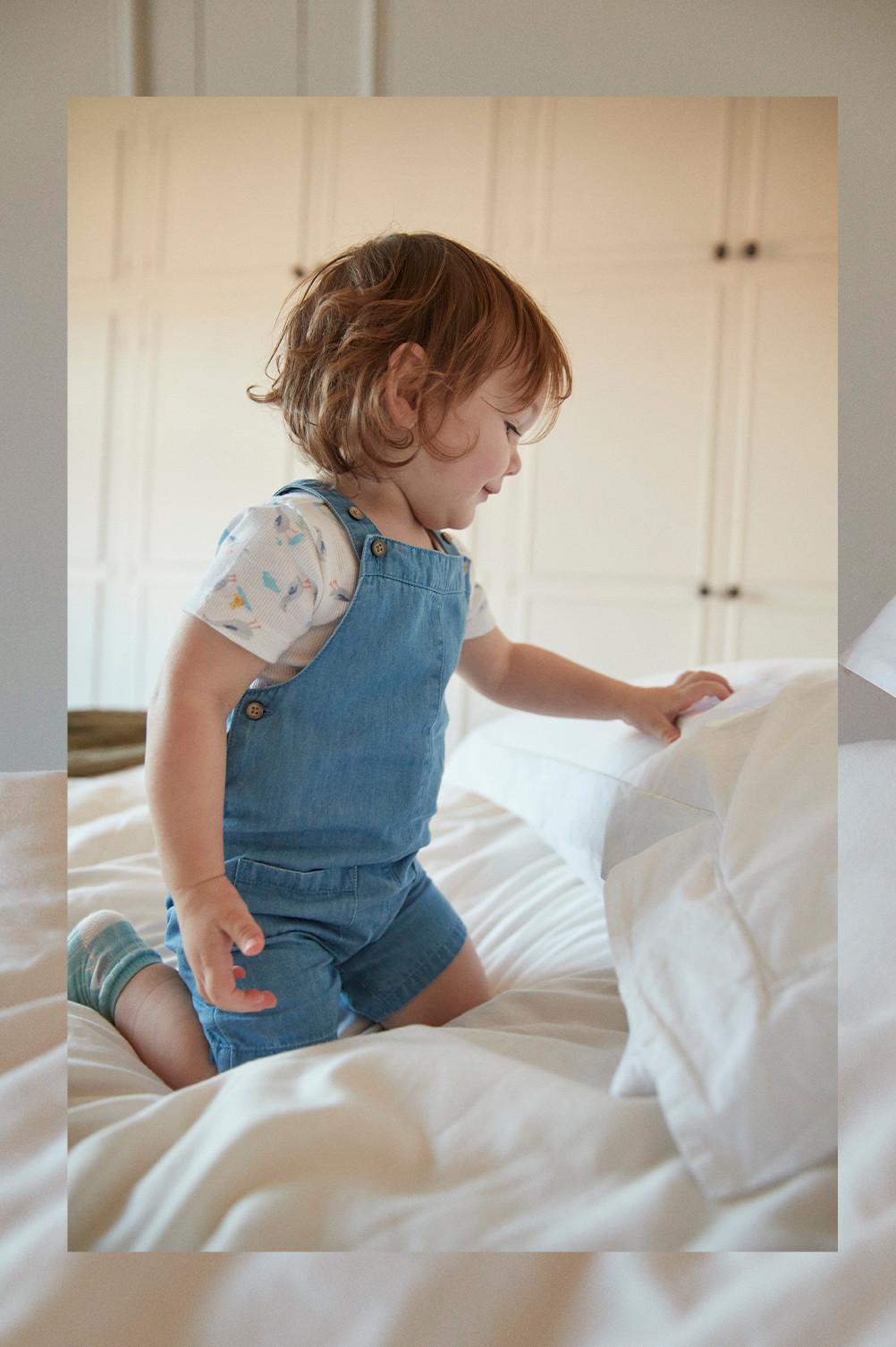 Baby wears denim dungarees, with a goose printed white tshirt