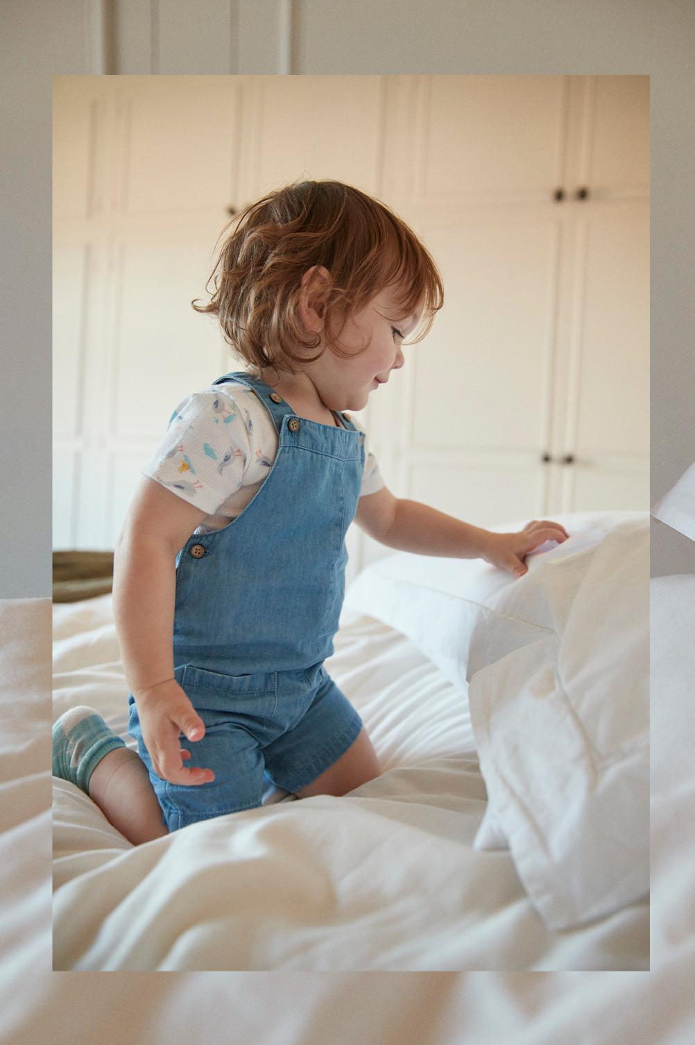 Baby in blauer Latzhose und weißem T-Shirt mit Gänseprint