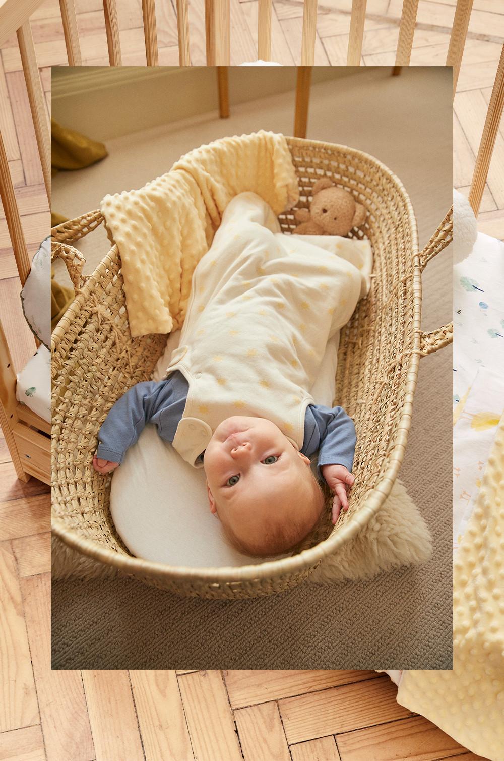 Bambino che dorme in una culla di vimini