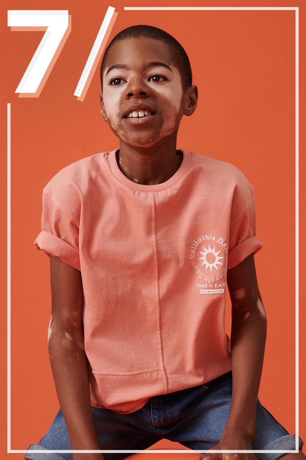 Enfant portant un T-shirt orange et un short en jean