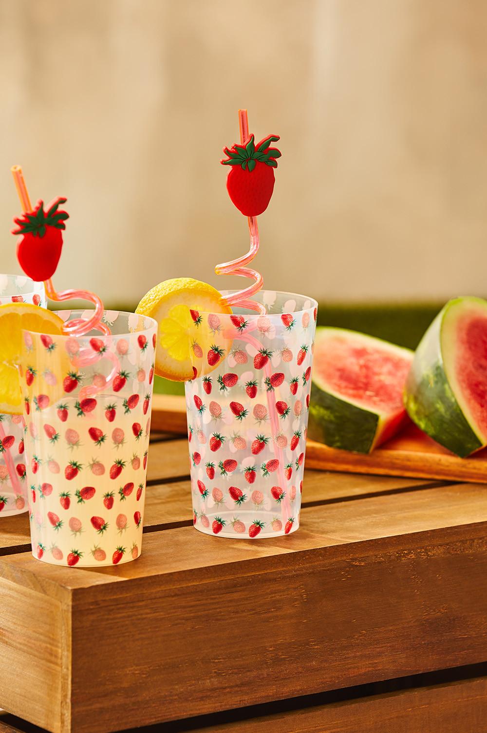Plastic red reusable straws with strawberries on, in matching cups also with a strawberry pattern