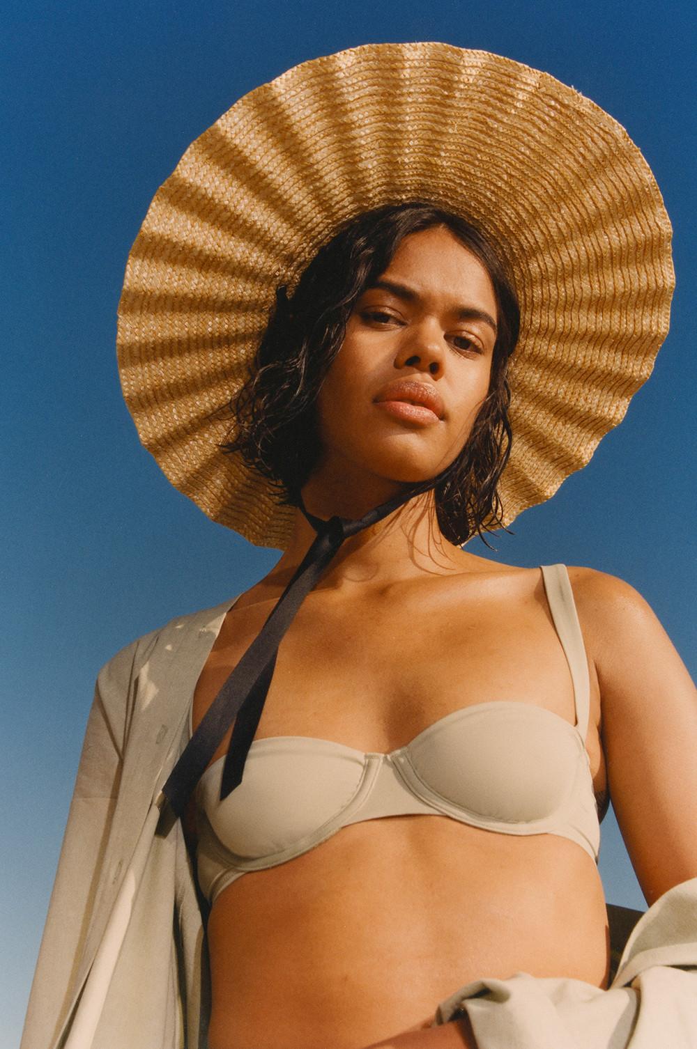 Model wears sage green underwired bikini top and straw hat