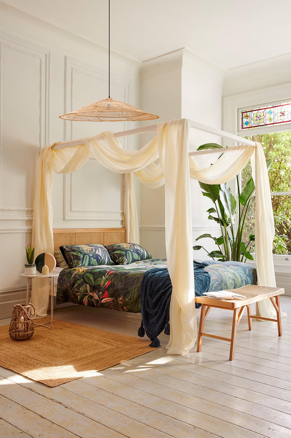 Bedroom with rattan furniture, teal printed bedsheets and faux plants