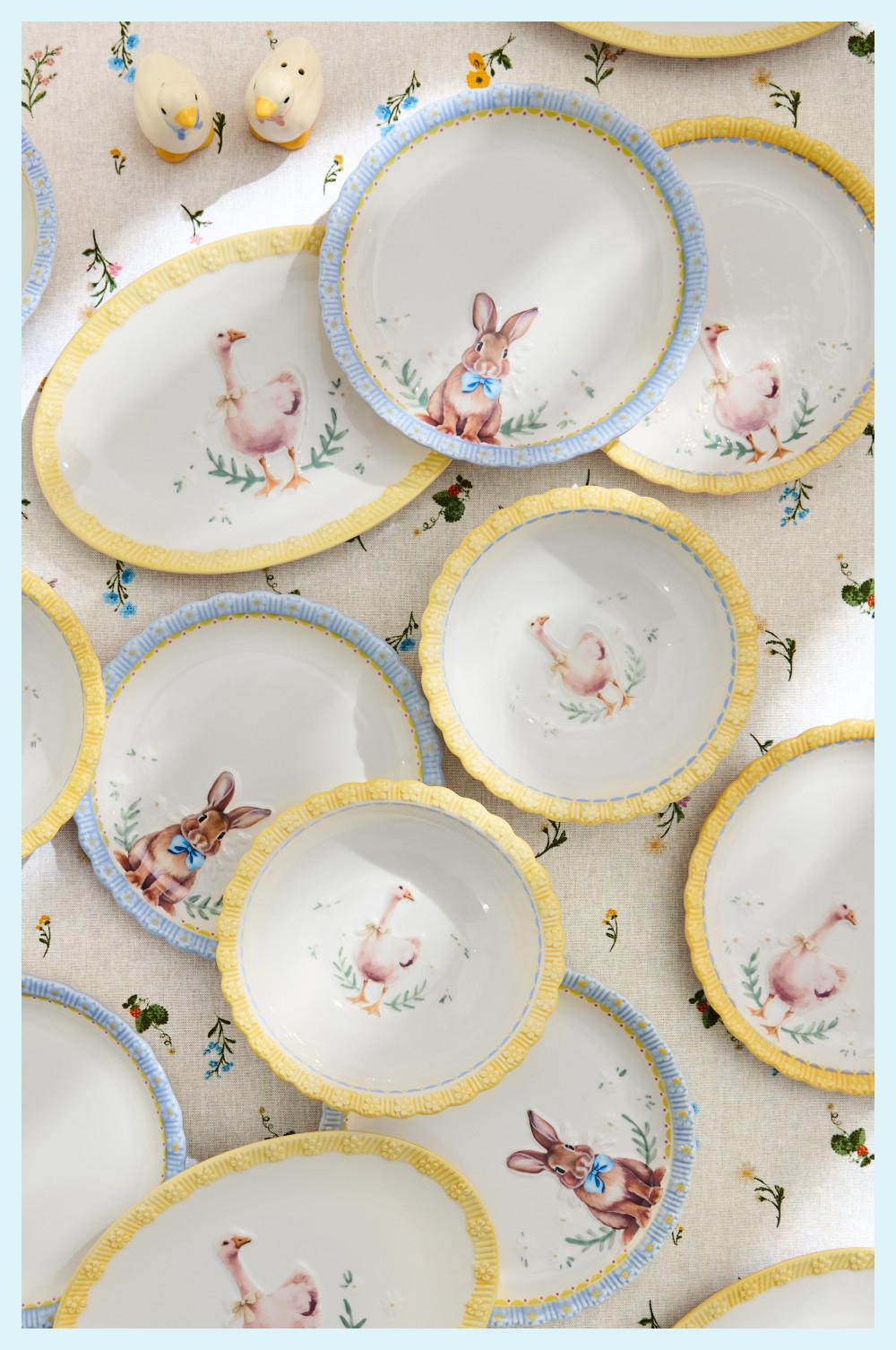 Easter-themed plates with painted bunnies and ducklings, featuring yellow and blue trim on a floral tablecloth.
