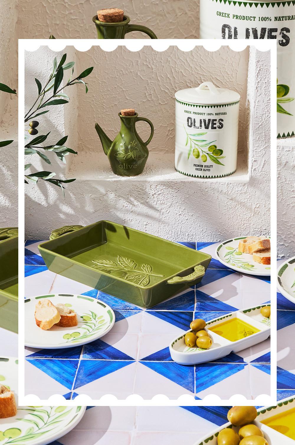 Küchenutensilien im Oliven-Design mit grünem Keramik-Ölkrug, Aufbewahrungsgefäß und Servierteller mit Brot und Oliven.