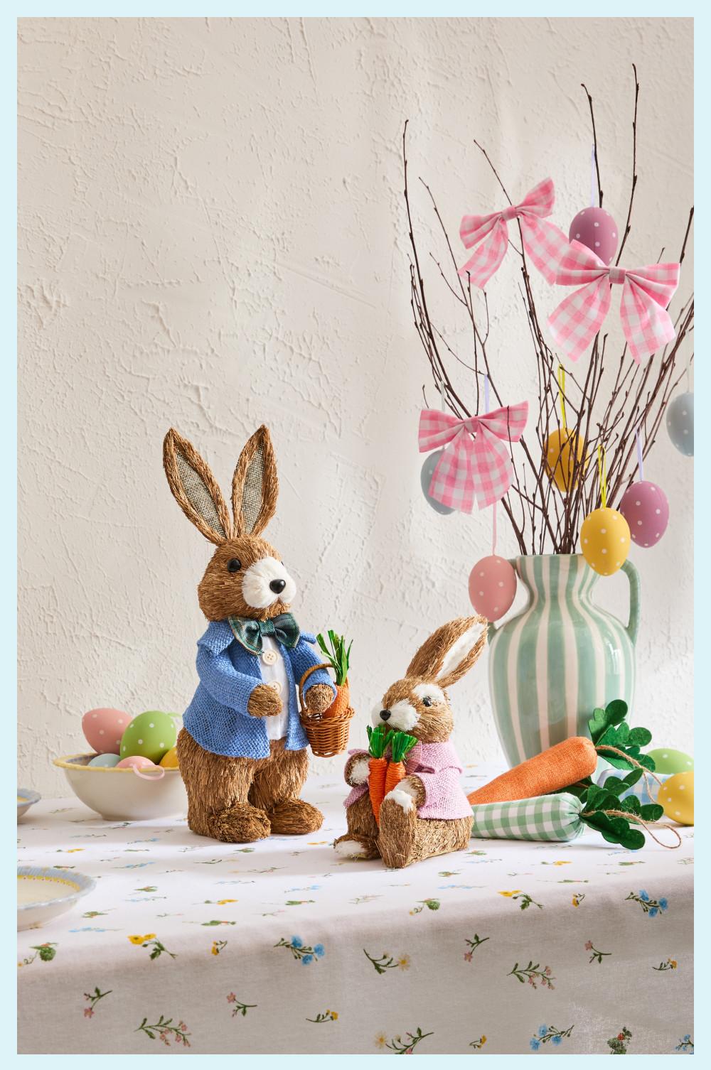 Easter-themed fireplace display with duck soft toys in outfits, spring flowers, and decorative carrots.