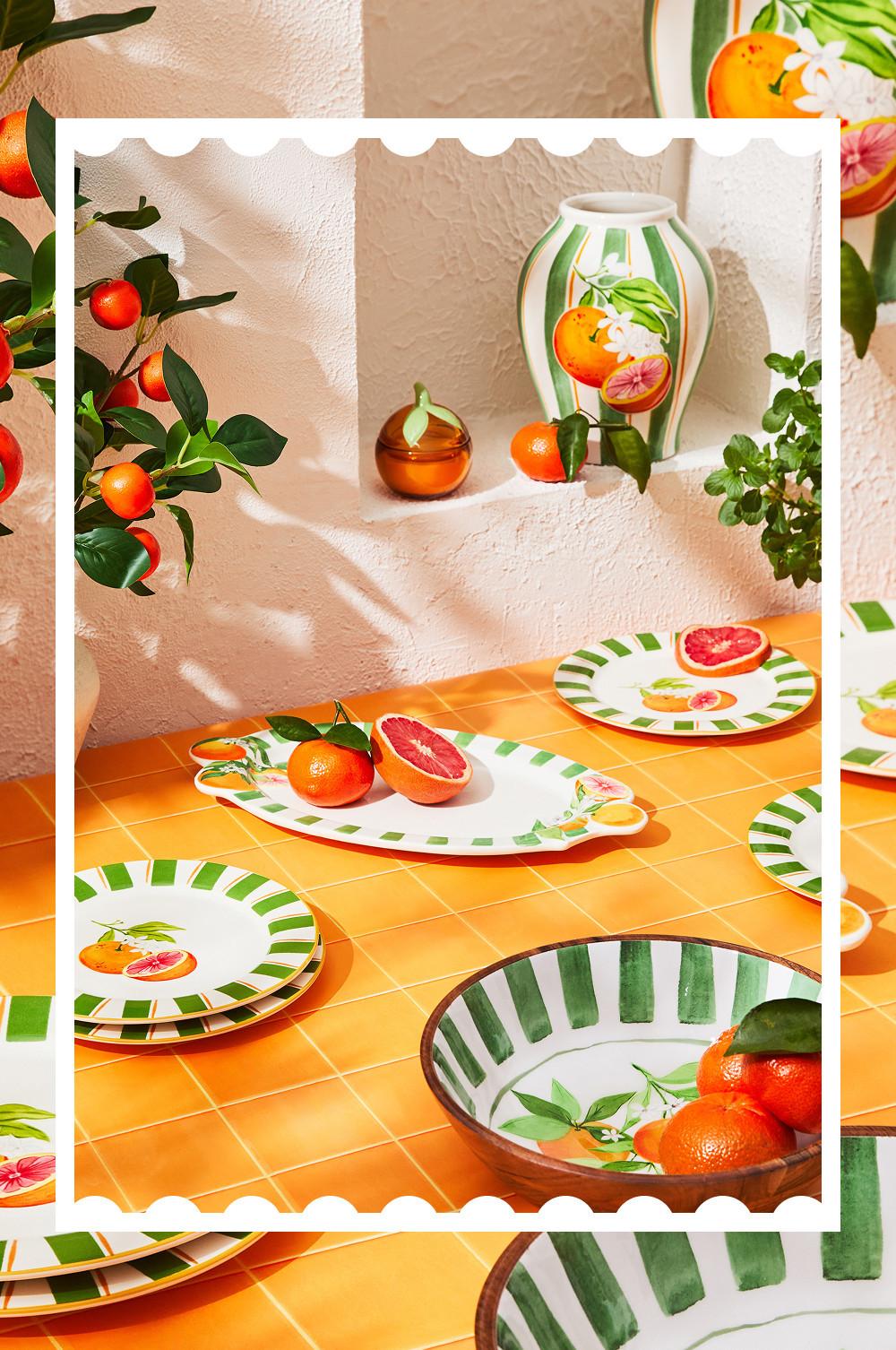 Geschirrkollektion mit Zitrusfrüchten als Thema, bestehend aus dekorativen Tellern, Schalen und Vasen mit Orangen- und Grapefruit-Motiven.