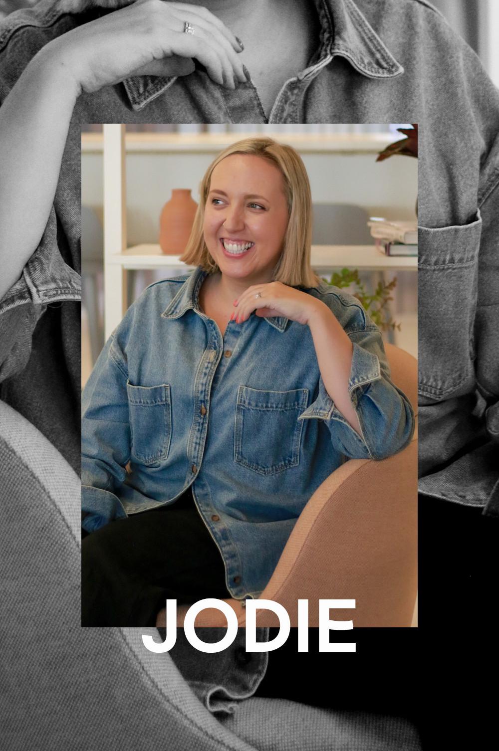 Jodie Spragg draagt ​​een blauwe spijkerblouse met lange mouwen en een zwarte broek.