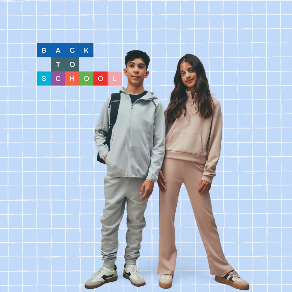 Back to school fashion featuring two teens wearing athleisure outfits - grey hoodie with backpack and beige tracksuit - on a blue grid background.