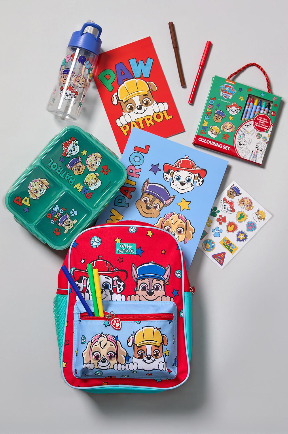 Collection of Paw Patrol children's items including backpack, lunch box, water bottle, notebooks and colouring set arranged together.