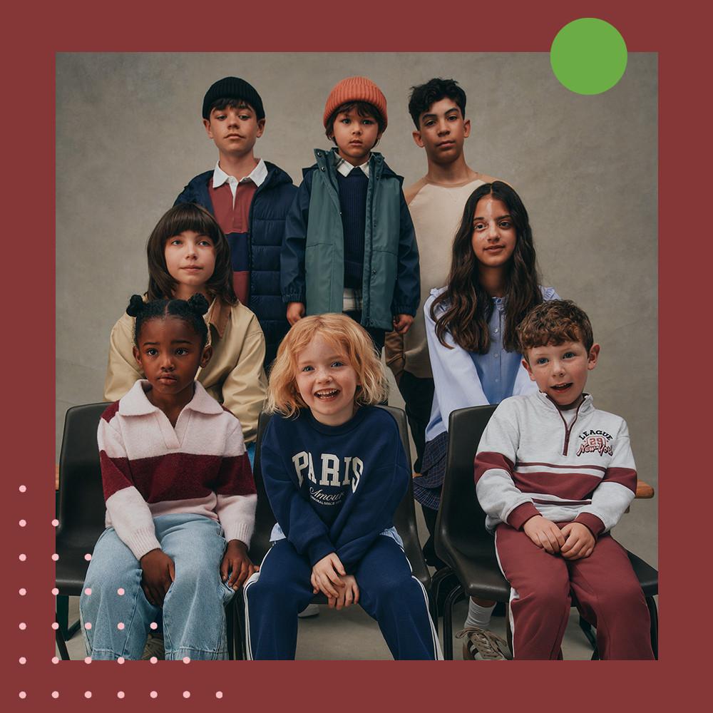 Group of children wearing fashionable fall clothing including puffer jackets, knit beanies, and casual sweaters.