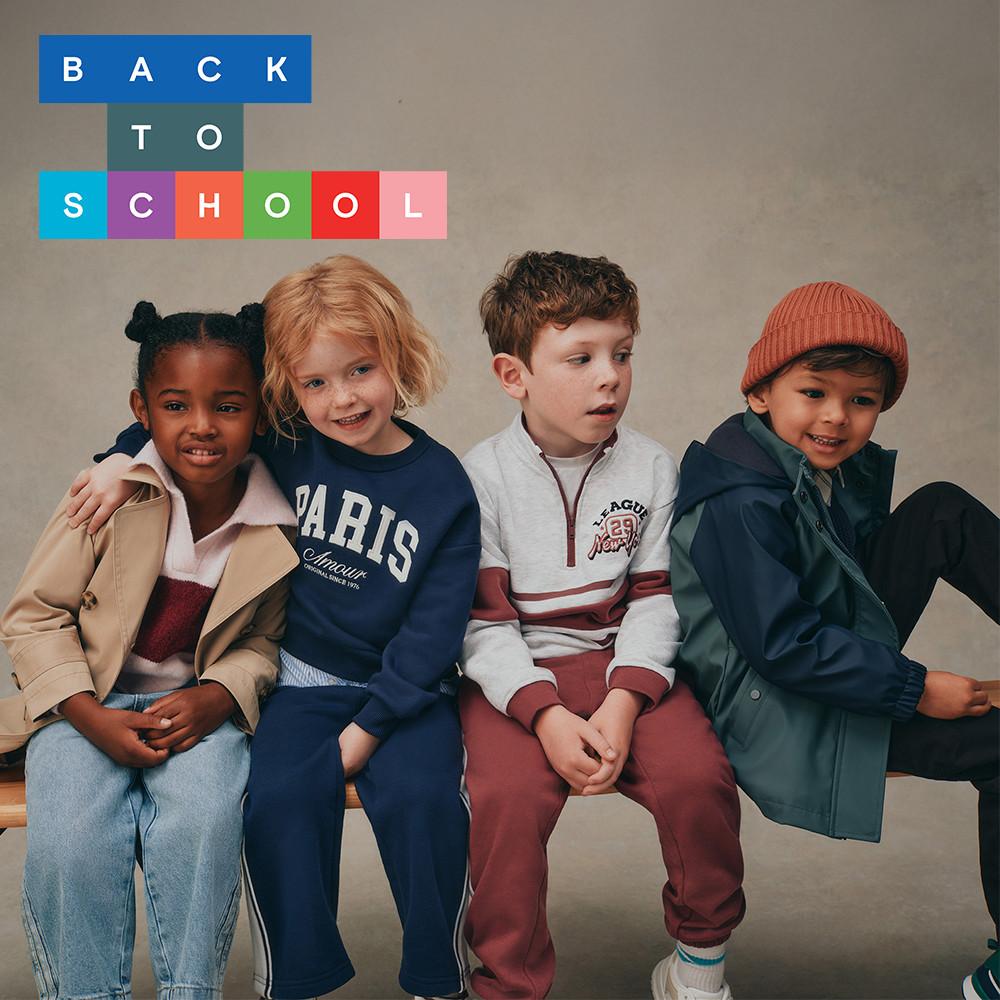 Children sitting together beneath colourful "BACK TO SCHOOL" text, wearing casual autumn clothing.