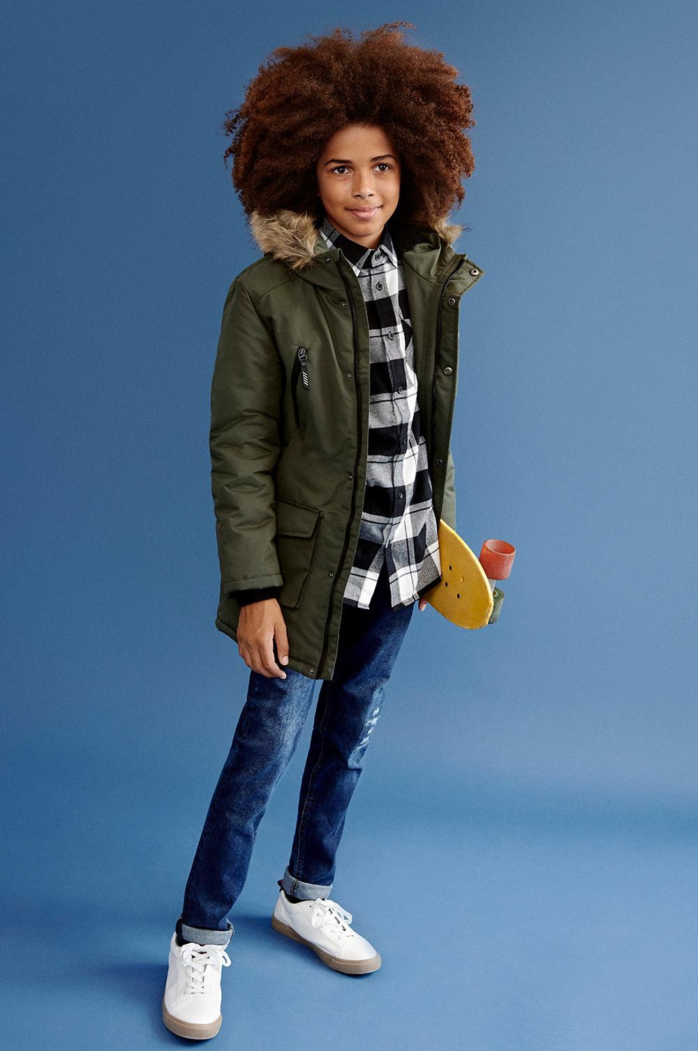 Child wearing a khaki jacket, flannel shirt and jeans