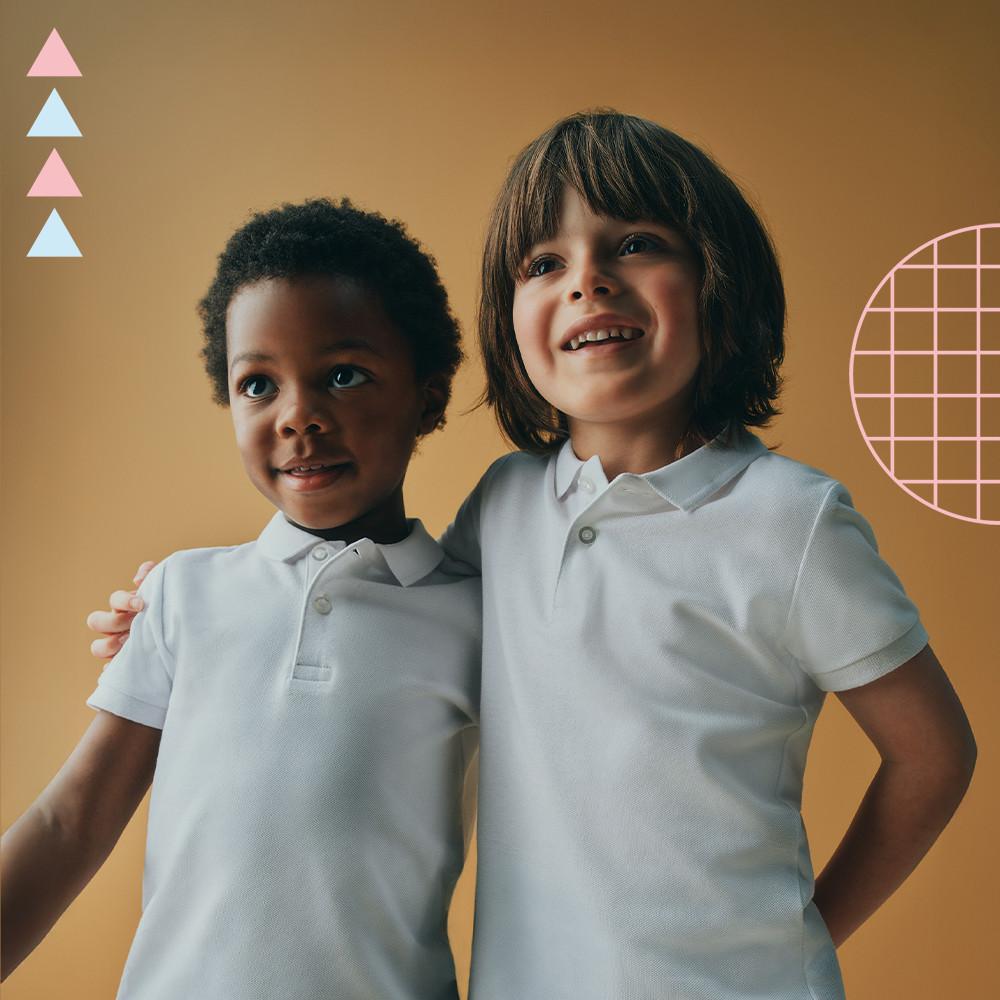 Two children wearing white polo shirts standing together against an orange background with decorative triangles.