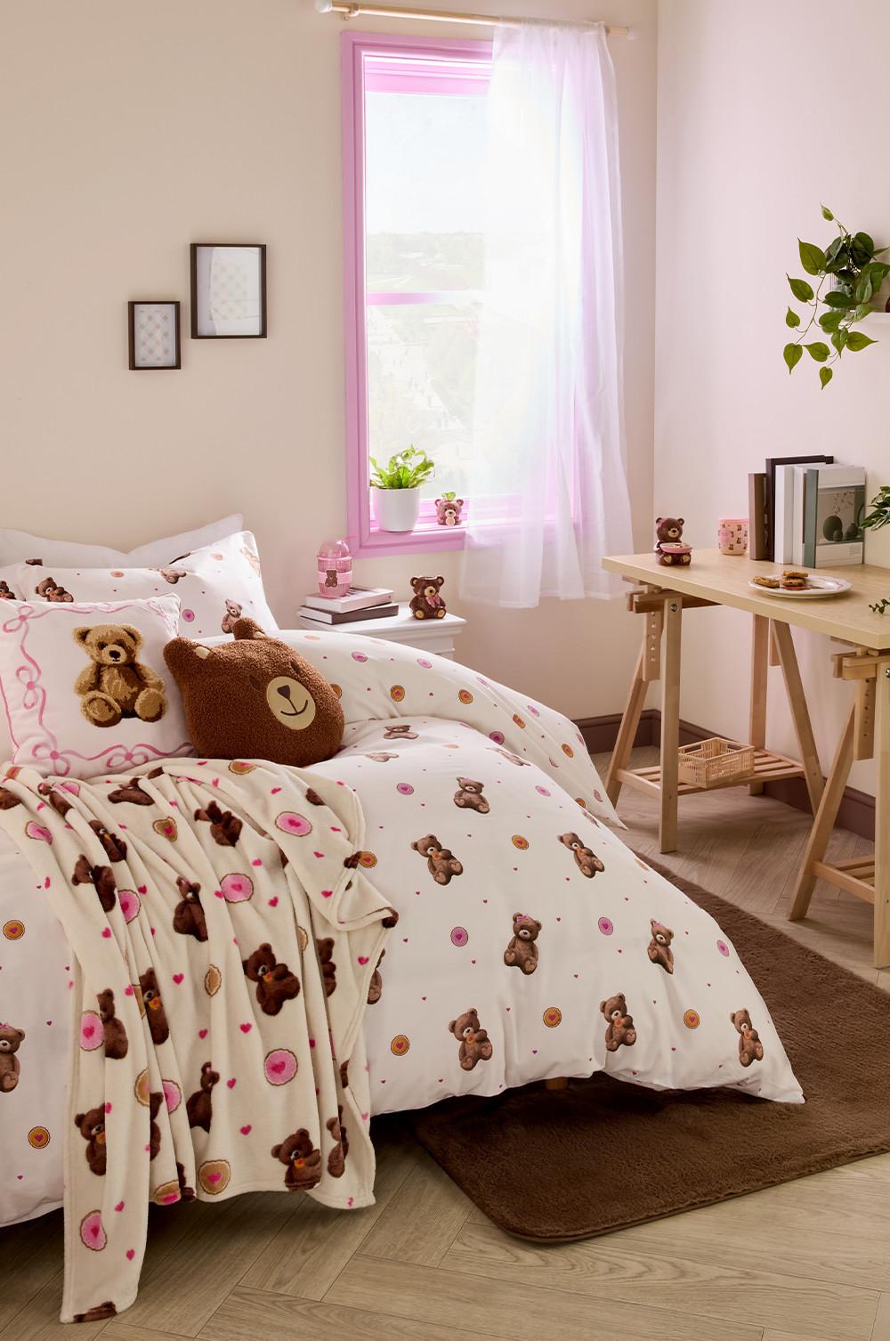 une chambre avec du linge de lit, des coussins et des mugs sur le thème de l’ours