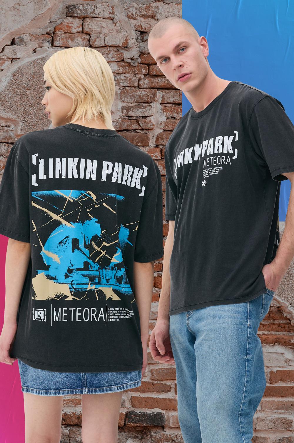 Two model wearing Linkin Park Meteora black T-shirts, one with a graphic back design, stand by a brick wall.
