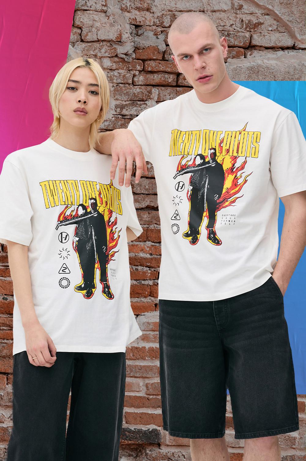 Two models wearing Twenty One Pilots graphic T-shirts, one in shorts, one in wide leg trousers.